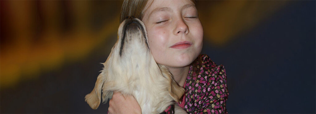 Une enfant autiste avec son chien dans un moment de complicité et de communication par les gestes.