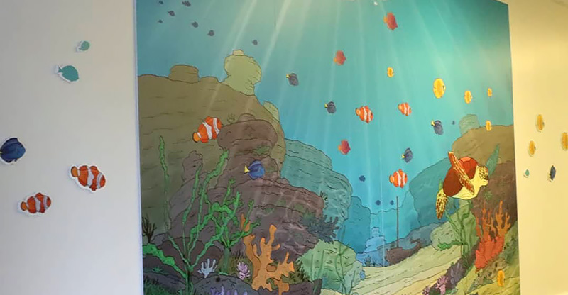 Une fresque murale décorée d'un univers aquatique féérique pour les enfants hospitalisés.