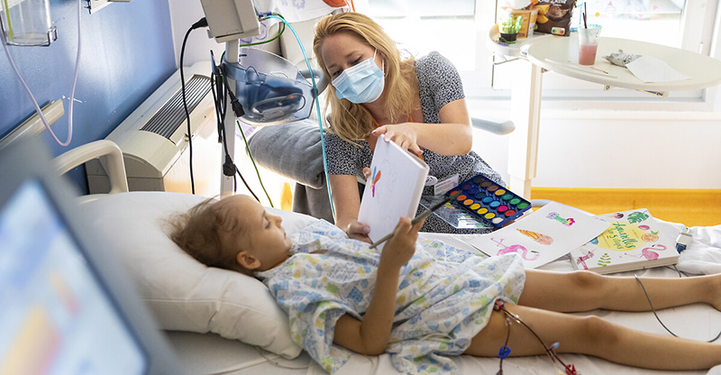 Un enfant hospitalisé réalise une peinture colorée dans son lit. 